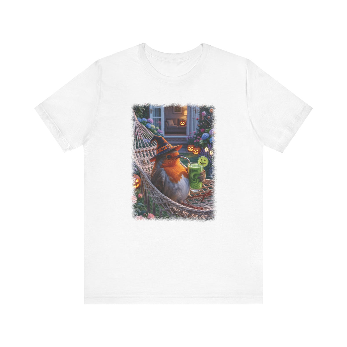 A white short-sleeve crewneck t-shirt featuring a colorful graphic print of a robin bird relaxing in a hammock on a porch during Halloween, surrounded by jack-o'-lanterns and a green drink.