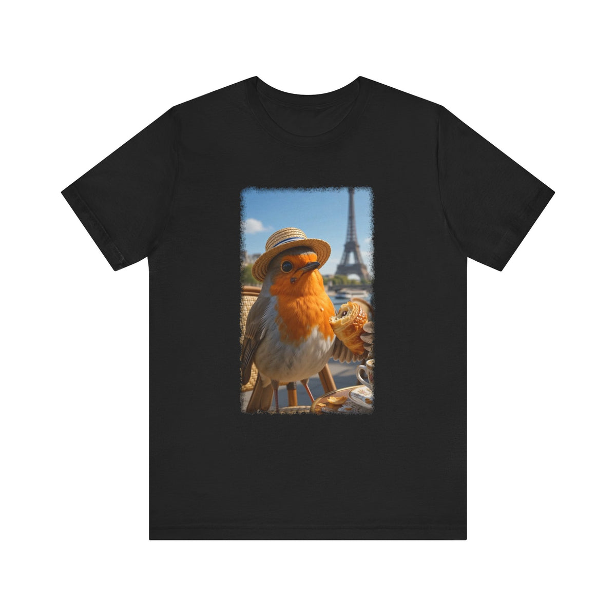 A dark black crewneck t-shirt featuring a rectangular graphic print of a robin wearing a straw hat with the Eiffel Tower and Paris street scene in the background.