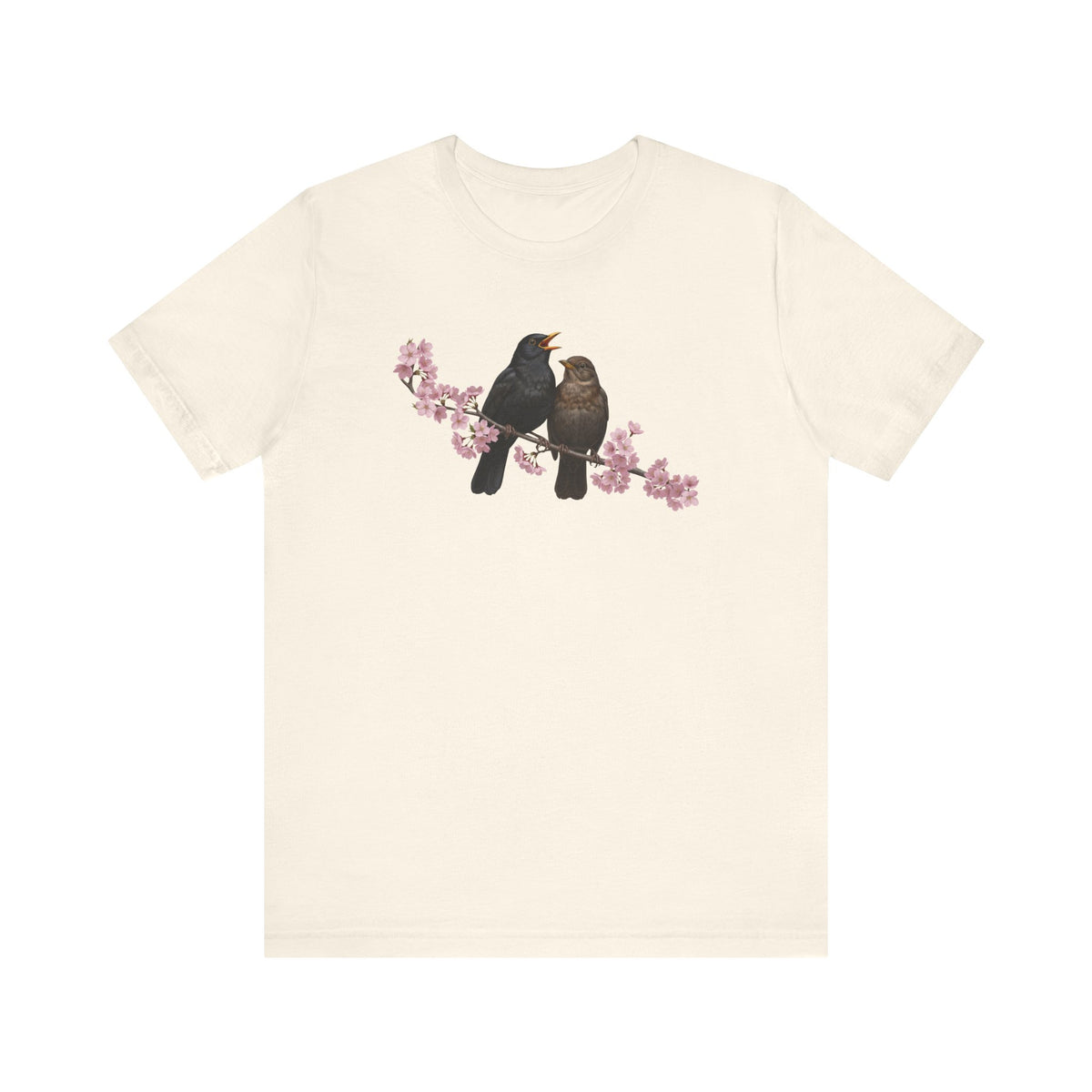 Beige t-shirt with a graphic of two birds on a branch with pink flowers on a white background