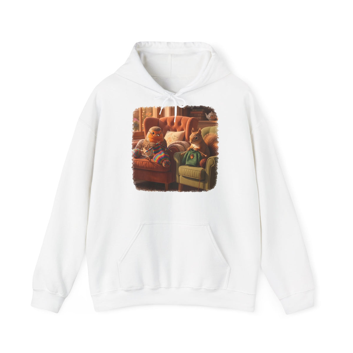 Ein weißer Kapuzenpullover mit einem quadratischen Grafikdruck auf der Brust, der eine gemütliche Wohnzimmerszene zeigt: Ein Rotkehlchen sitzt neben einem Eichhörnchen im grünen Pullover auf einem Sessel, und beide stricken.