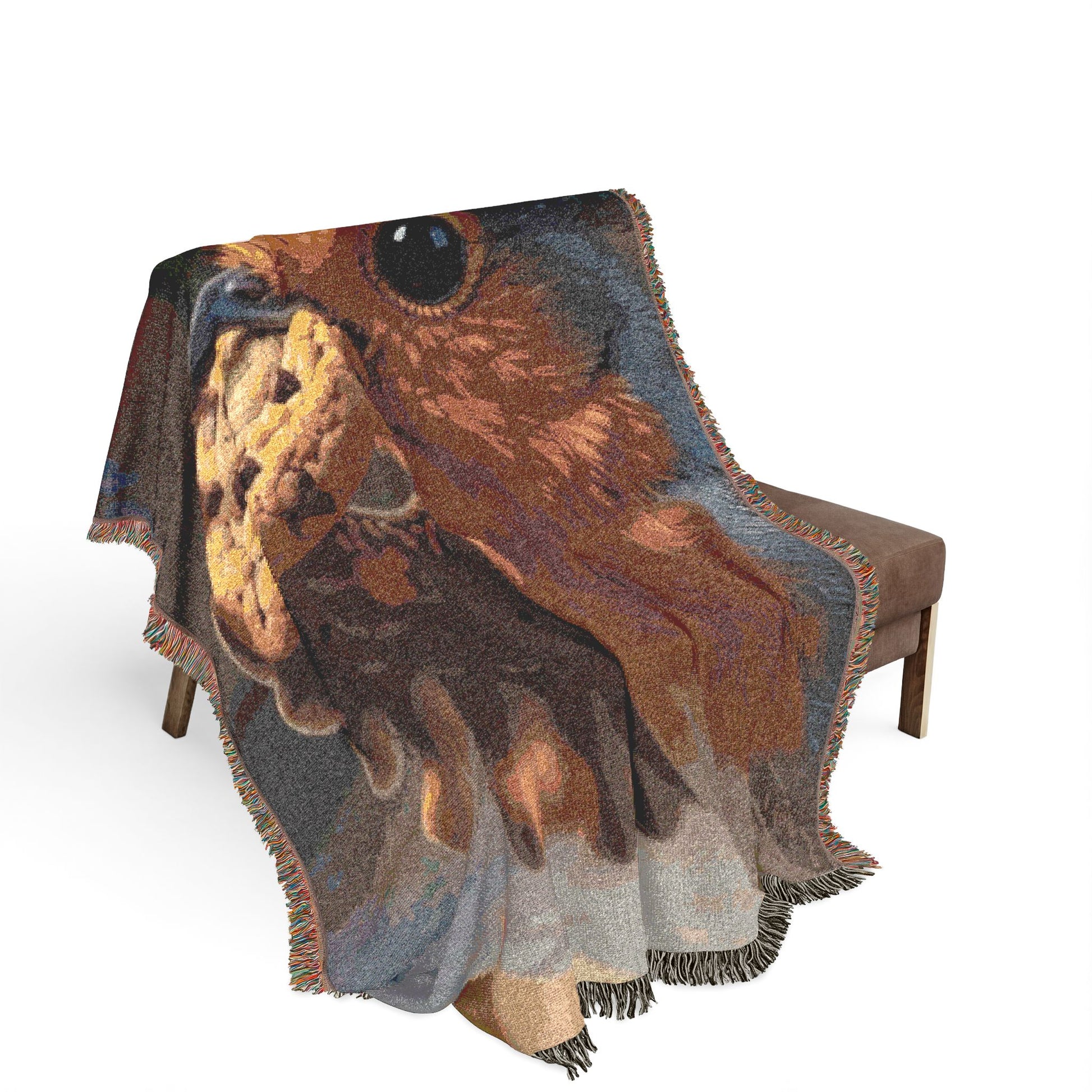 A woven throw blanket with fringe is draped over a brown upholstered bench. The blanket features a large, detailed graphic print of an robin bird in warm brown, orange, and gray tones against a white studio background.
