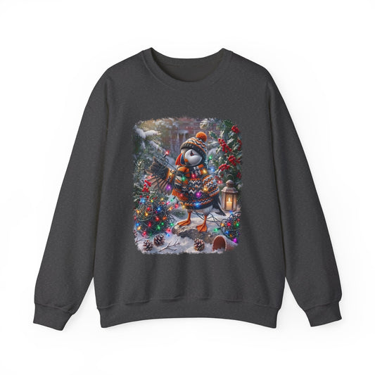 A dark gray crewneck sweatshirt featuring a colorful graphic print of a puffin dressed in winter clothing and a hat, holding a guitar amidst Christmas trees and snow.