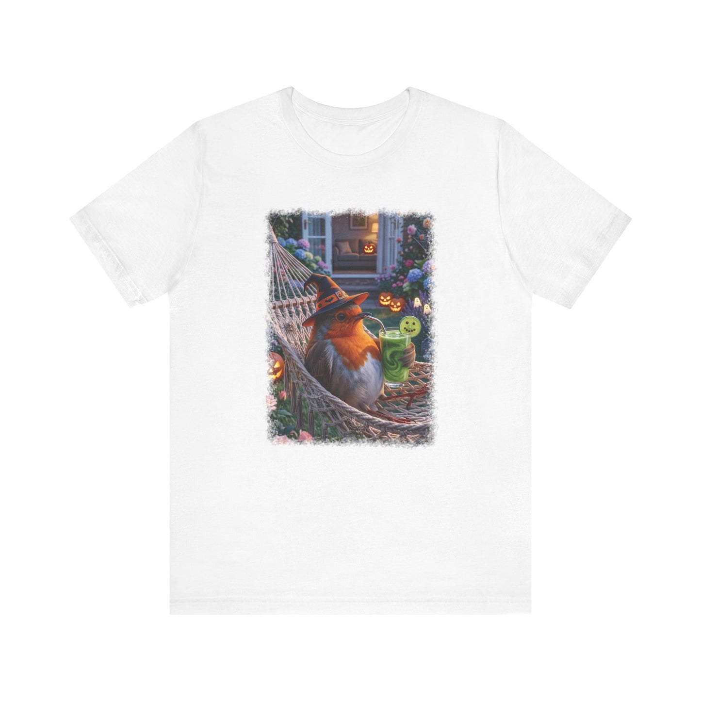 A white short-sleeve crewneck t-shirt featuring a colorful graphic print of a robin bird relaxing in a hammock on a porch during Halloween, surrounded by jack-o'-lanterns and a green drink.