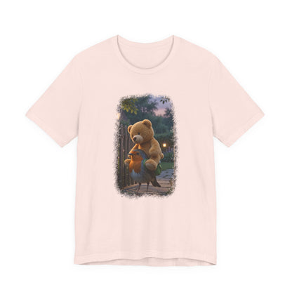 Pinkes T-Shirt aus Baumwolle. Auf der Brust ist eine witzige digitale Illustration aufgedruckt: Ein niedliches Rotkehlchen namens Rosi steht im Vorgarten und versucht, einen riesigen Kirmes-Teddybären in einen viel zu kleinen grünen Frosch-Rucksack zu quetschen.
