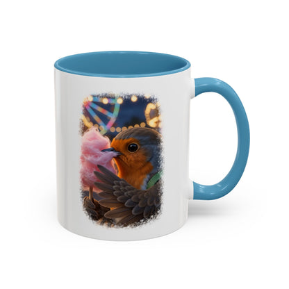 A white ceramic mug with a blue interior and handle, featuring a printed graphic of a robin bird eating pink cotton candy against a dark background with colorful bokeh lights.