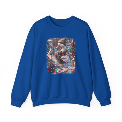 A royal blue crewneck sweatshirt featuring a square graphic print on the chest of a snowy goose wearing a knit hat and scarf, surrounded by festive red berries and greenery.