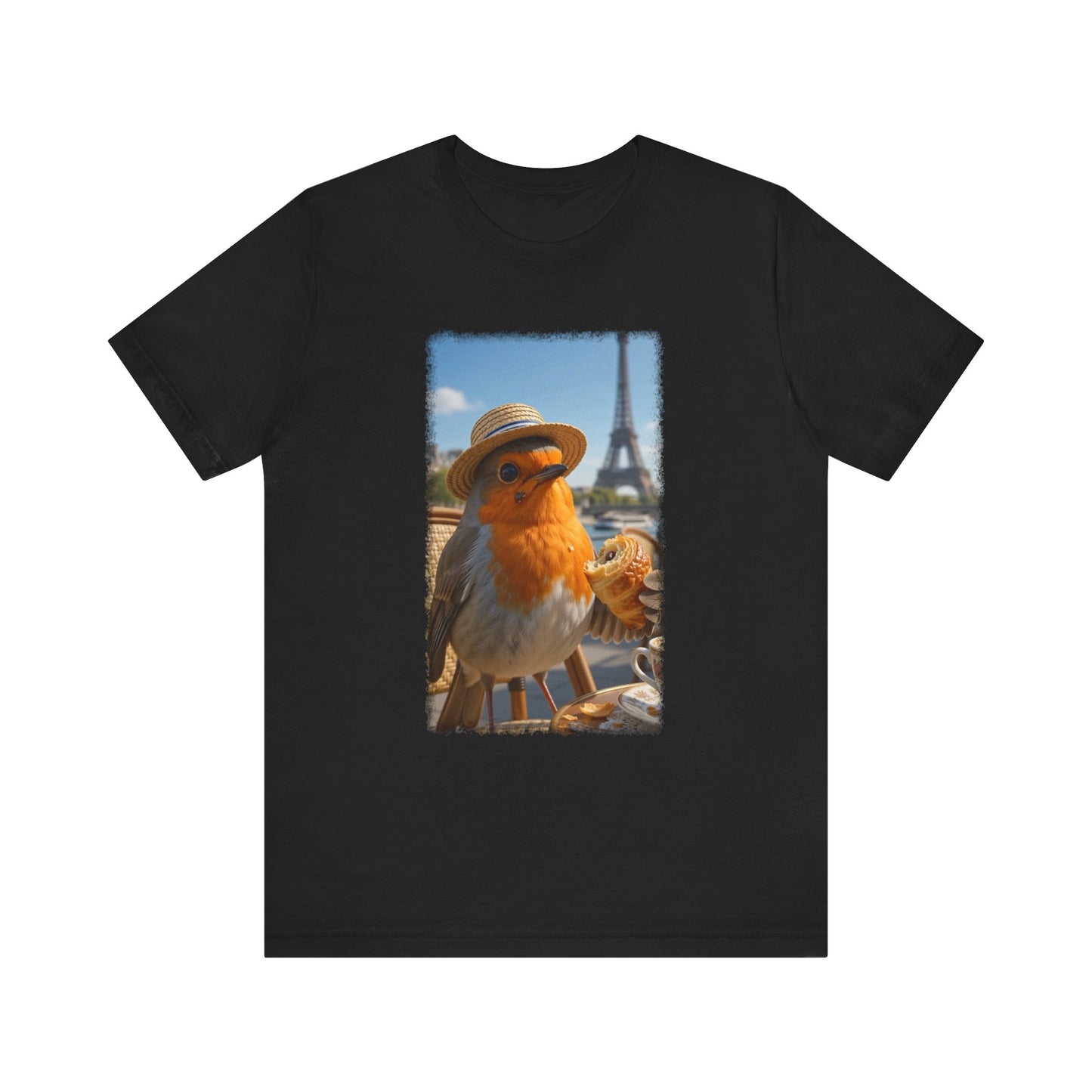 A dark black crewneck t-shirt featuring a rectangular graphic print of a robin wearing a straw hat with the Eiffel Tower and Paris street scene in the background.
