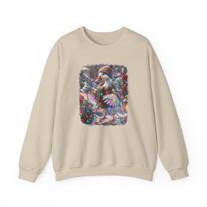 A beige crewneck sweatshirt featuring a square graphic print on the chest of a snowy goose wearing a knit hat and scarf, surrounded by festive Christmas decorations.