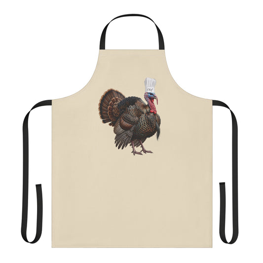 A beige apron with black neck and waist straps, featuring a central graphic of a wild turkey wearing a chef's hat and holding a spatula, set against a plain white background.