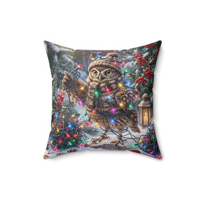 A square decorative throw pillow featuring a festive winter scene with a brown owl wearing a knit hat, surrounded by colorful Christmas lights, snow, pine branches, and a lantern, shown on a plain white background.
