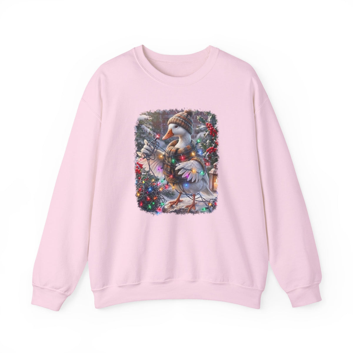 A light pink crewneck sweatshirt featuring a square graphic print on the chest of a snowy goose wearing a knit hat and scarf, surrounded by festive greenery and red berries.