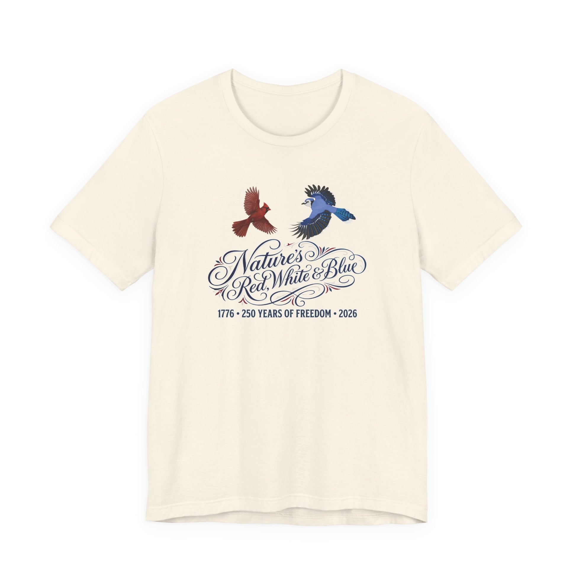 A premium Bella Canvas 3001 unisex t-shirt featuring a detailed design of a Blue Jay and a Northern Cardinal flying above the vintage calligraphy text Nature's Red, White & Blue, commemorating 250 years of freedom (1776-2026).