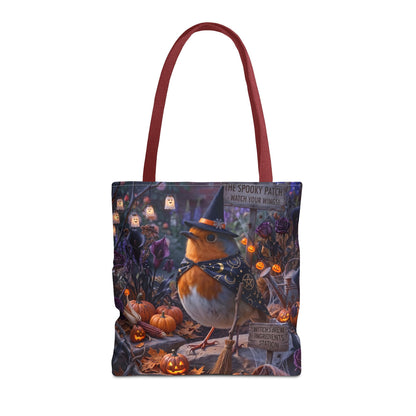 A tote bag with a detailed Halloween-themed illustration featuring a robin in a witch hat and bow tie, surrounded by pumpkins, ghosts, and spooky decorations. The bag has dark red shoulder straps and is shown against a plain white background.