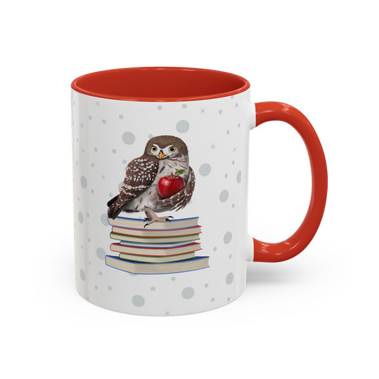A white ceramic mug with a red interior and handle, decorated with a printed illustration of a brown owl perched on a stack of books and holding a red apple. The mug is shown on a clean white background.