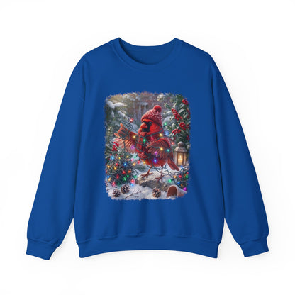 A royal blue crewneck sweatshirt featuring a large, colorful graphic print of a festive cardinal wearing a red knit hat and scarf, standing in a snowy Christmas tree scene.