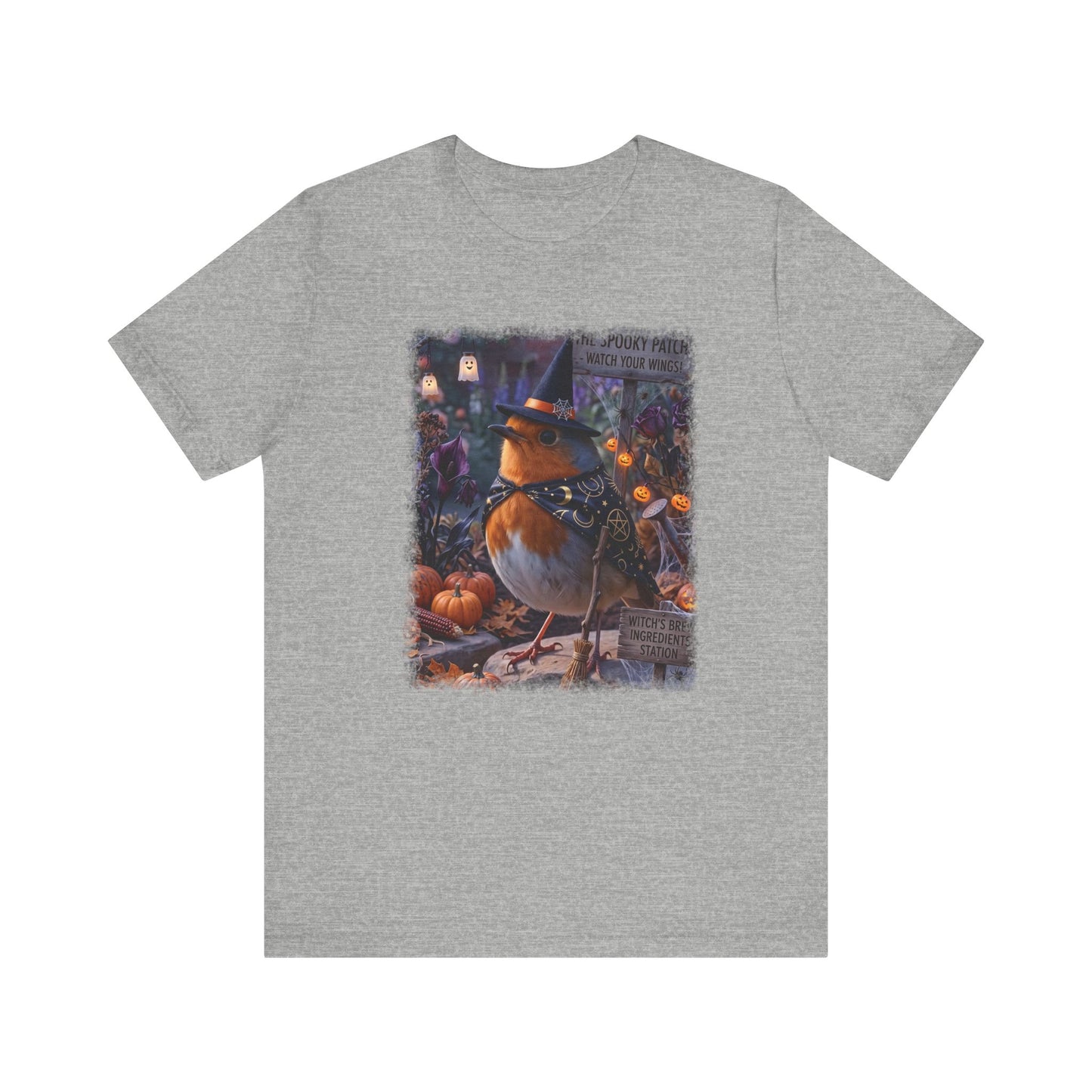 A heather gray short-sleeve crewneck t-shirt featuring a colorful graphic print of a robin dressed as a witch sitting among pumpkins on a porch.