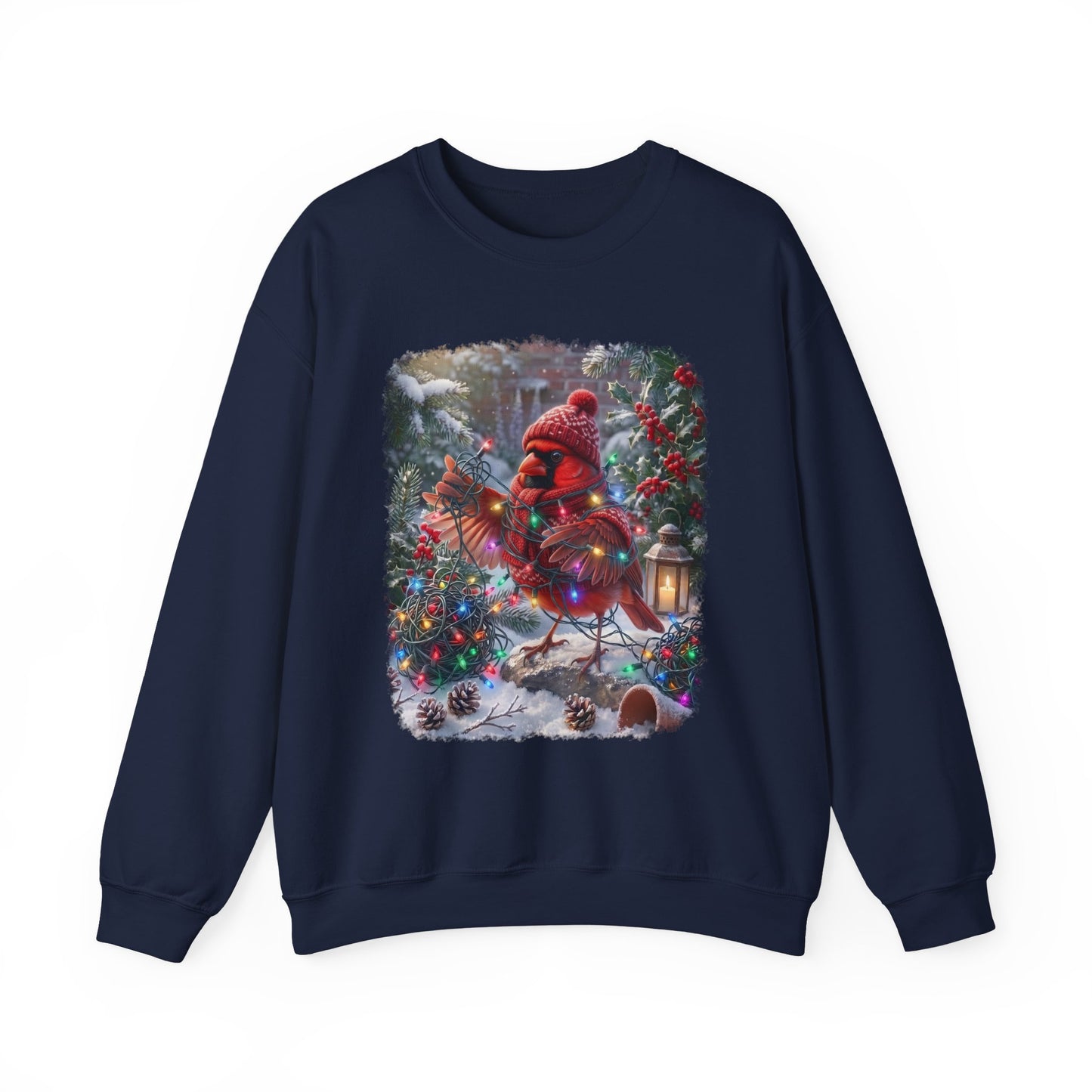 A navy blue crewneck sweatshirt featuring a large square graphic print on the front. The graphic depicts a festive Christmas scene with a red cardinal wearing a red knit hat and scarf, standing in a snowy yard decorated with a lit Christmas tree and a lantern.