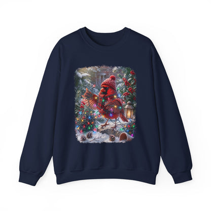 A navy blue crewneck sweatshirt featuring a large square graphic print on the front. The graphic depicts a festive Christmas scene with a red cardinal wearing a red knit hat and scarf, standing in a snowy yard decorated with a lit Christmas tree and a lantern.