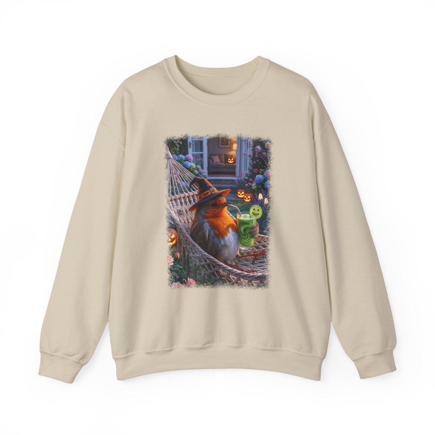 A beige crewneck sweatshirt featuring a colorful graphic print of a robin bird dressed as a witch sitting in a hammock surrounded by Halloween decorations.