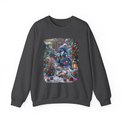 A dark gray crewneck sweatshirt featuring a large, colorful graphic print of a blue jay wearing a winter hat and scarf, nestled among decorated Christmas trees and pinecones in a snowy outdoor scene.
