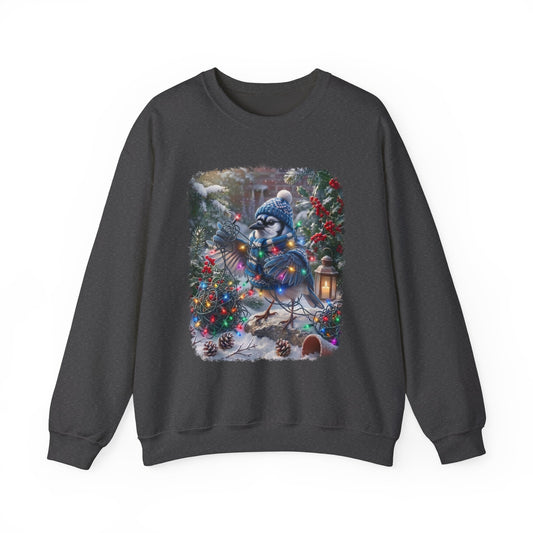A dark gray crewneck sweatshirt featuring a large, colorful graphic print of a blue jay wearing a winter hat and scarf, nestled among decorated Christmas trees and pinecones in a snowy outdoor scene.