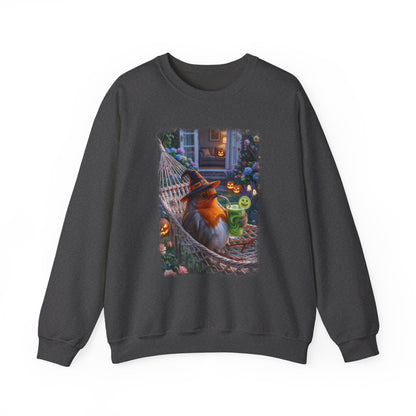 A dark charcoal gray crewneck sweatshirt featuring a colorful graphic print of a robin bird dressed in a witch hat relaxing in a hammock surrounded by Halloween decorations.