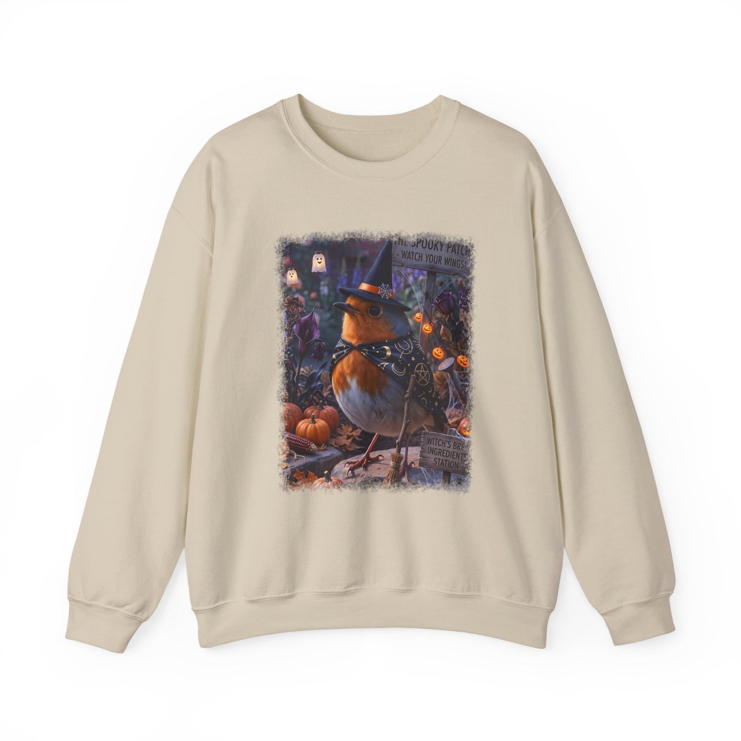 A beige crewneck sweatshirt featuring a large, detailed graphic print of a witch robin bird wearing a pointed hat, surrounded by pumpkins and autumn decorations.