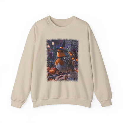 A beige crewneck sweatshirt featuring a large, detailed graphic print of a witch robin bird wearing a pointed hat, surrounded by pumpkins and autumn decorations.