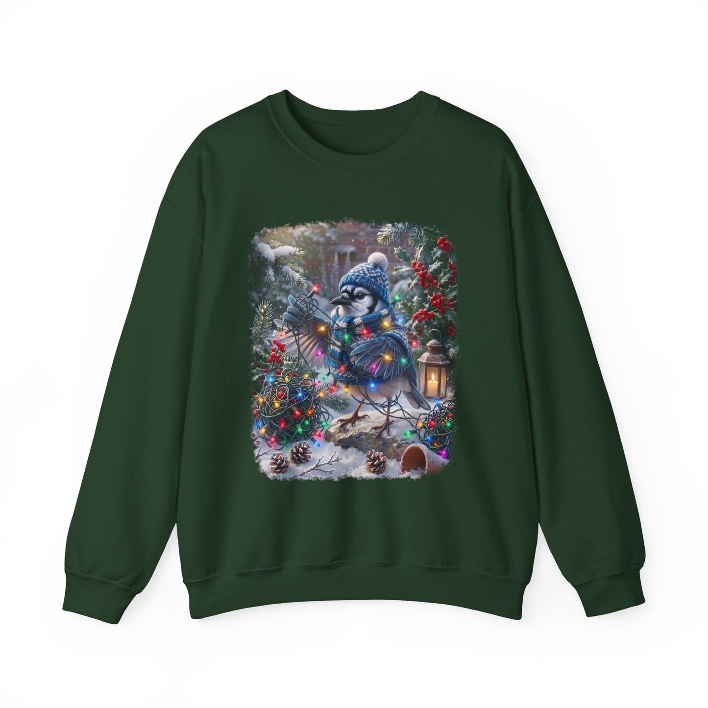 A dark green crewneck sweatshirt featuring a large square graphic print on the front of a snowy winter scene with a blue jay wearing a knit hat and scarf, surrounded by Christmas trees and ornaments.