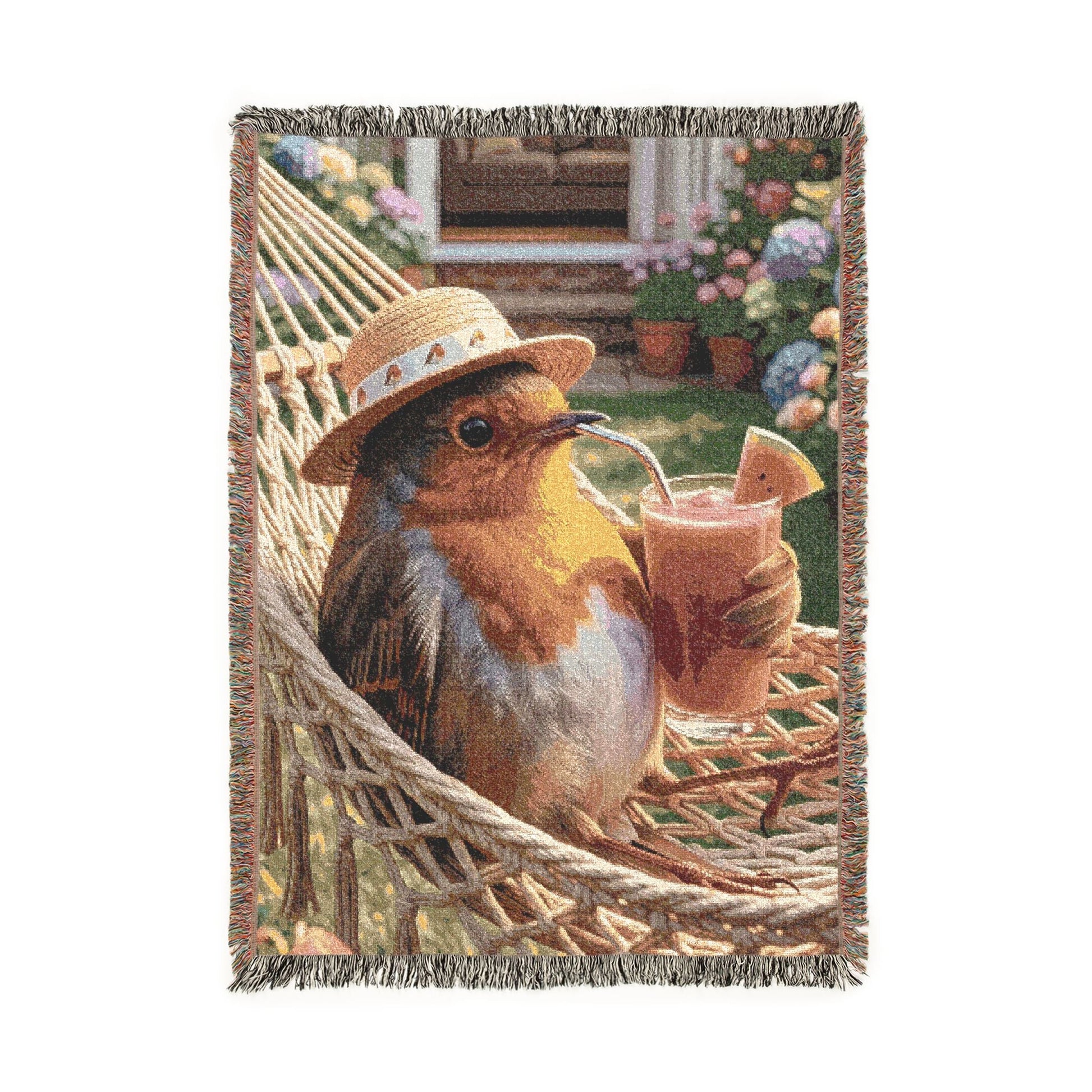 A woven throw blanket featuring a whimsical illustration of a robin bird wearing a straw hat and holding a smoothie, set against a rustic garden and porch background with fringed edges.