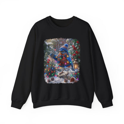A black crewneck sweatshirt featuring a large, colorful graphic print on the front of a blue bird dressed in winter clothing, surrounded by Christmas trees, ornaments, and warm holiday lights.