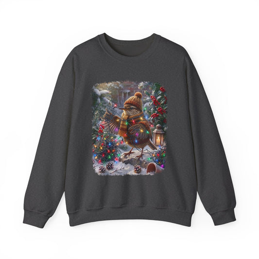 A dark gray crewneck sweatshirt featuring a large, colorful graphic print of a Christmas wren wearing a knit hat and scarf, standing in a snowy winter garden decorated with lights and pinecones.