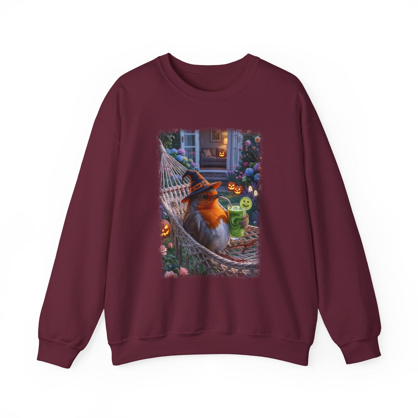 A maroon crewneck sweatshirt featuring a large graphic print on the front of a robin bird wearing a witch hat and sitting in a hammock surrounded by Halloween decorations.