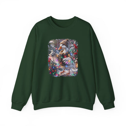 A dark green crewneck sweatshirt featuring a square graphic print on the chest of a snowy goose wearing a knit hat and scarf, surrounded by winter flowers and a lantern.