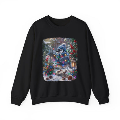 A black crewneck sweatshirt featuring a large, colorful graphic print of a blue jay wearing a winter hat and scarf, surrounded by Christmas trees, ornaments, and a lantern in a snowy outdoor setting.