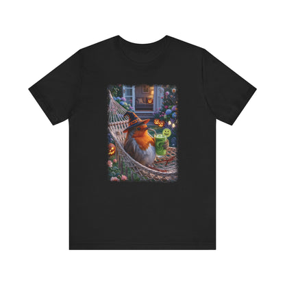 A black short-sleeve crewneck t-shirt featuring a colorful graphic print of a robin bird relaxing in a hammock surrounded by Halloween decorations, shown against a plain white background.