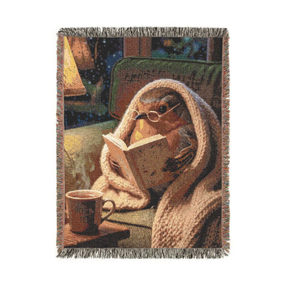 A woven throw blanket featuring a cozy scene of a robin bird wrapped in a knitted sweater and reading a book, with a mug that reads 'Rosi's Tea'. The blanket has fringed edges and is shown against a plain white background.