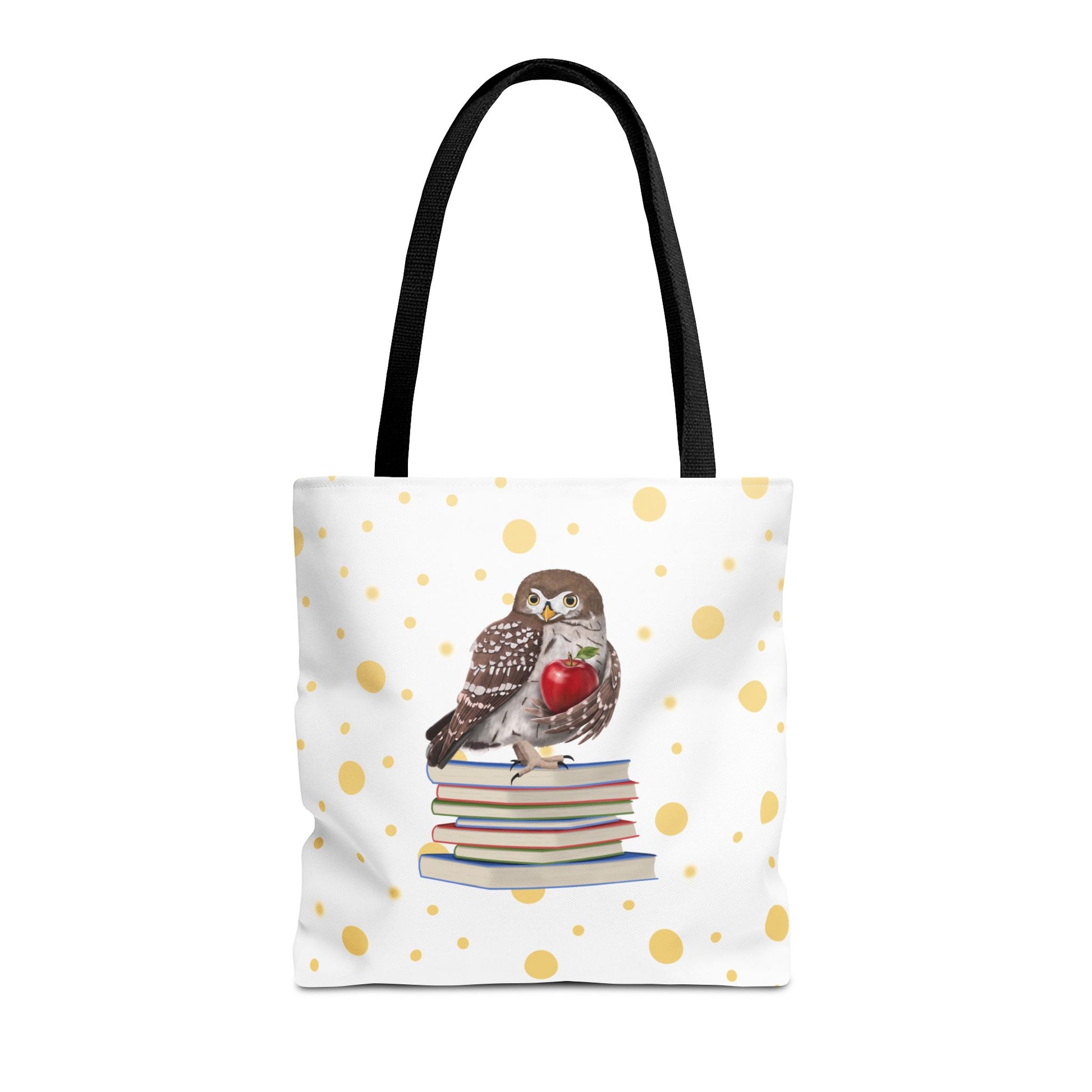 A white tote bag with black shoulder straps, decorated with a central illustration of a brown owl perched on a stack of books holding a red apple, and a scattered gold polka dot pattern across the bag.