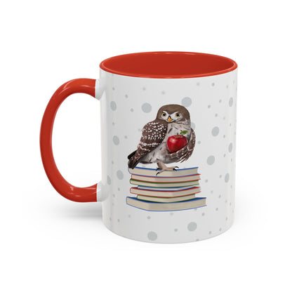 A white ceramic mug with a red handle and red interior, decorated with a printed illustration of a small owl perched on a stack of books and holding a red apple. The mug is shown on a clean white background.