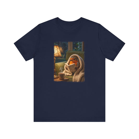 Digital gemalte Illustration eines niedlichen Rotkehlchens, das eingekuschelt in eine Decke auf dem Sofa sitzt und ein Buch liest, mit sanft auslaufenden künstlerischen Acryl-Pinselkanten auf einem T-Shirt.