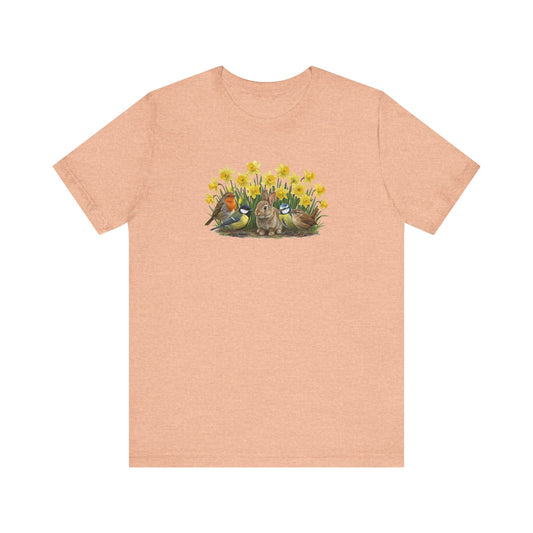 Peach T-Shirt mit großem Frühlings-Aufdruck: Ein Kaninchen sitzt zwischen gelben Osterglocken, umgeben von Rotkehlchen, Blaumeise, Kohlmeise und Zaunkönig.
