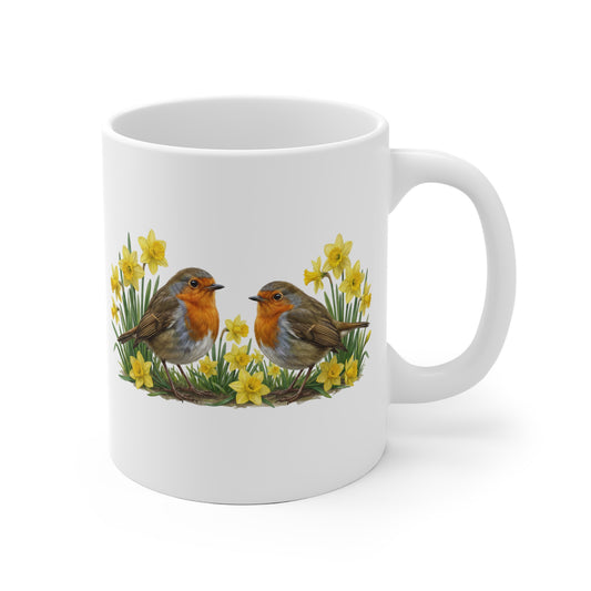 weißes tasse mit zwei gemalten rotkehlchen die umgeben sind von gelben osterglocken