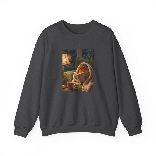 Soft unisex crewneck sweatshirt featuring a colorful front print. The digital illustration shows the cute bird Robin Rosi wrapped in a cozy blanket reading a book on the sofa. A great gift for a birdwatcher or bird lover.