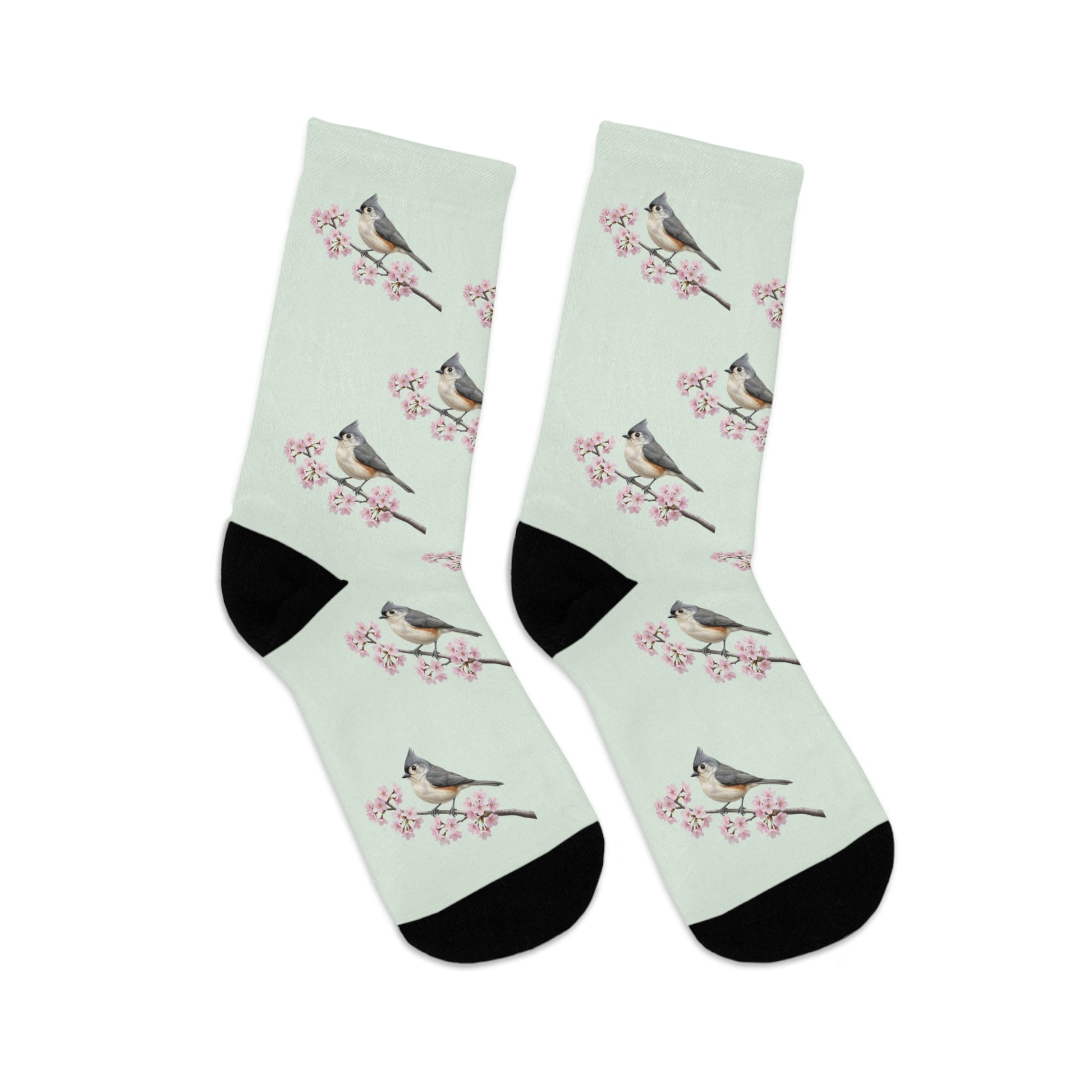 A pair of comfortable sage green socks featuring a seamless all-over print pattern of a vibrant Tufted Titmouse and delicate cherry blossoms. Eco-friendly birdwatching apparel.
