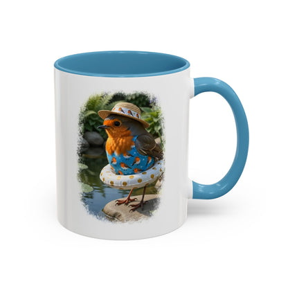 Weiße Keramiktasse mit farbigem Henkel und Innenseite. Das aufgedruckte Motiv zeigt eine digitale Illustration von einem niedlichen Rotkehlchen namens Rosi, das einen blauen Badeanzug und einen weißen Schwimmring mit goldenen Punkten trägt und an einem sonnigen Gartenteich steht.
