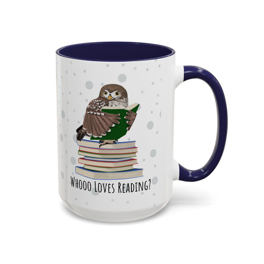 A white ceramic mug with a dark navy blue interior and handle, featuring a printed illustration of an owl perched on a stack of books and the text 'WHOOO LOVES READING?'.