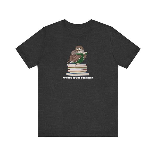 A dark heather gray short-sleeve t-shirt with a graphic of an owl perched on a stack of books, with the text 'whooo loves reading?' printed below, displayed on a solid white background.