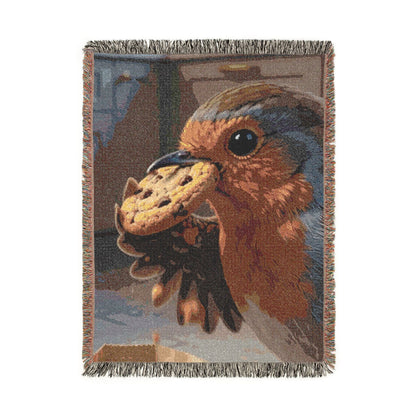 A rectangular woven throw blanket with fringed edges, featuring a detailed tapestry-style illustration of a robin bird pecking a cookie. The design has earthy tones of brown, beige, gray, and blue, shown against a plain white background.