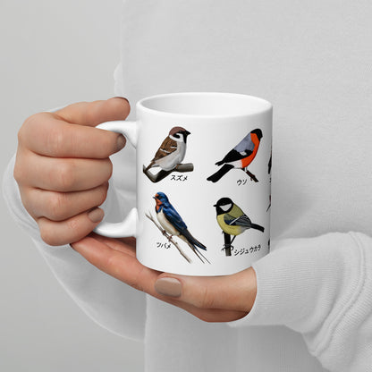 White mug with bird illustrations held by a person against a light gray background